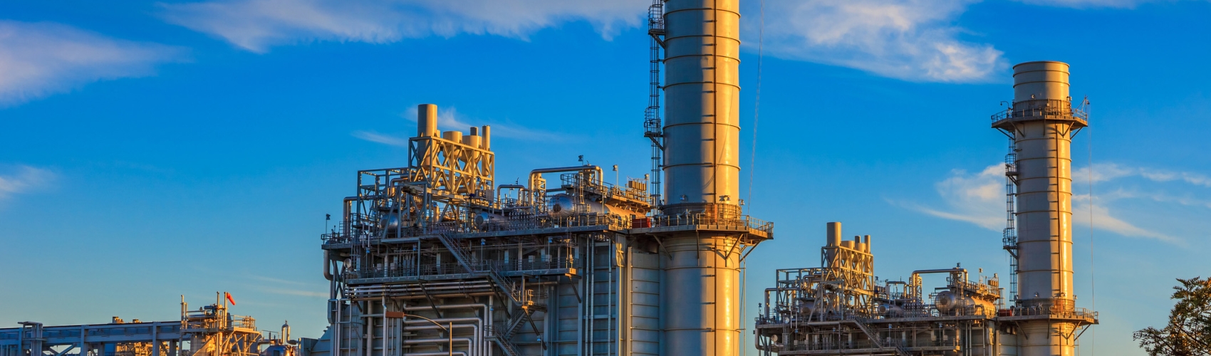Natural gas fired turbine power plant with it's cooling towers rising into a cloud filled blue sky