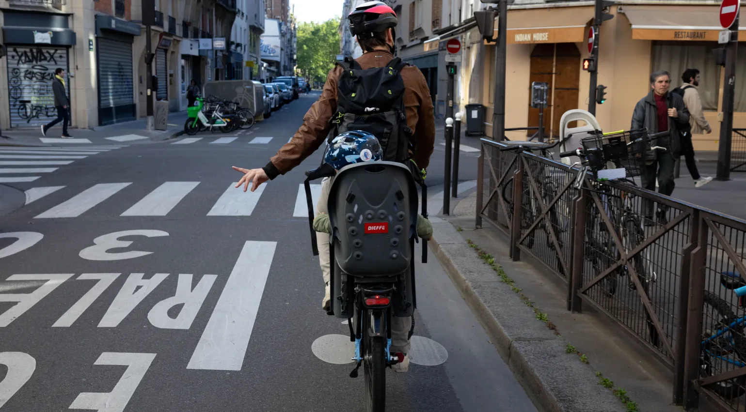 Photograph of a man cycling with his son in the backseat in Paris